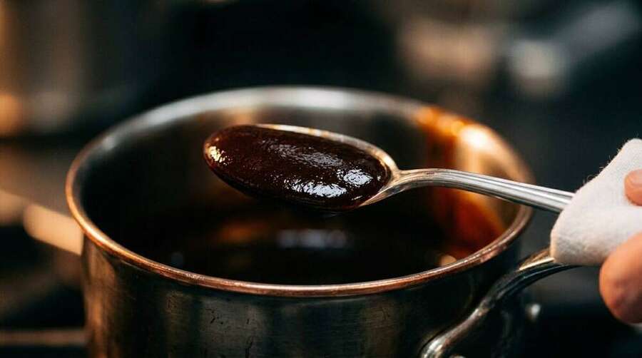A deeply reduced demi-glace coating the back of a silver spoon, deep mahogany colour, glossy mirror-like surface